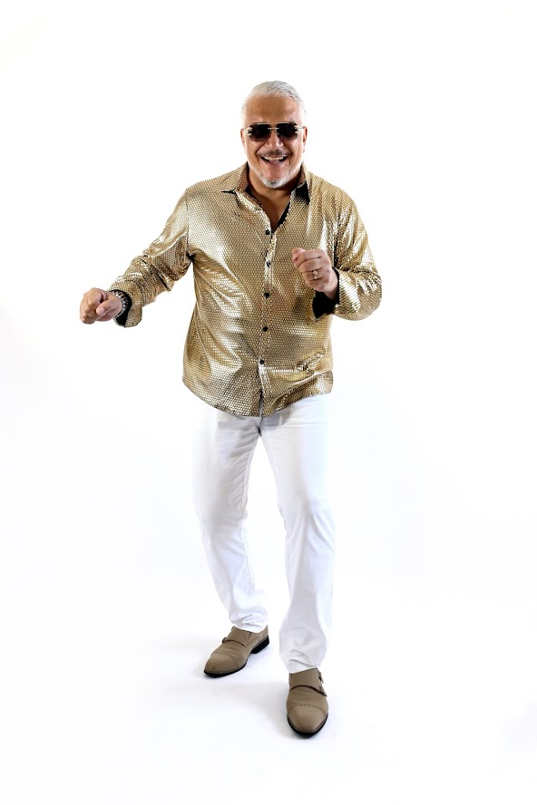 Ganzkörperfoto eines älteren Mannes im goldfarbenes Hemd, festliche Disco-Stimmung,lächelnd und spielerisch.